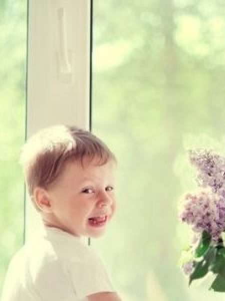 Image depict a child sitting next to a window.