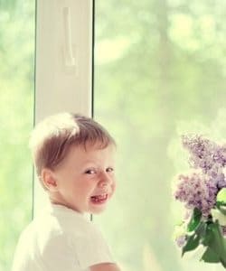 Image depict a child sitting next to a window.