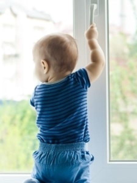 Image depicts a chhild standing in front of a window.