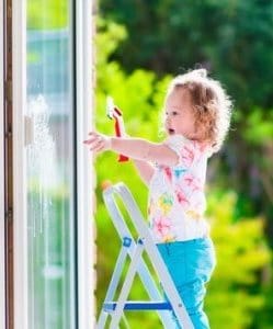 Image depicts a child cleaning a vinyl window.
