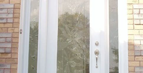 Image depicts a white fiberglass entry door in a home.