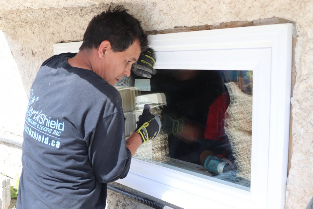 Image depicts a technician installing a new window.