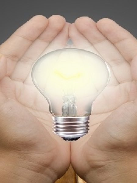 Image depicts light bulb in hands.