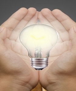 Image depicts light bulb in hands.