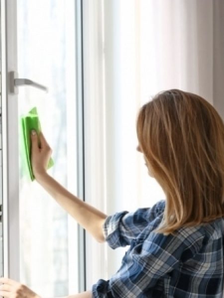 Image depicts woman cleaning a window.