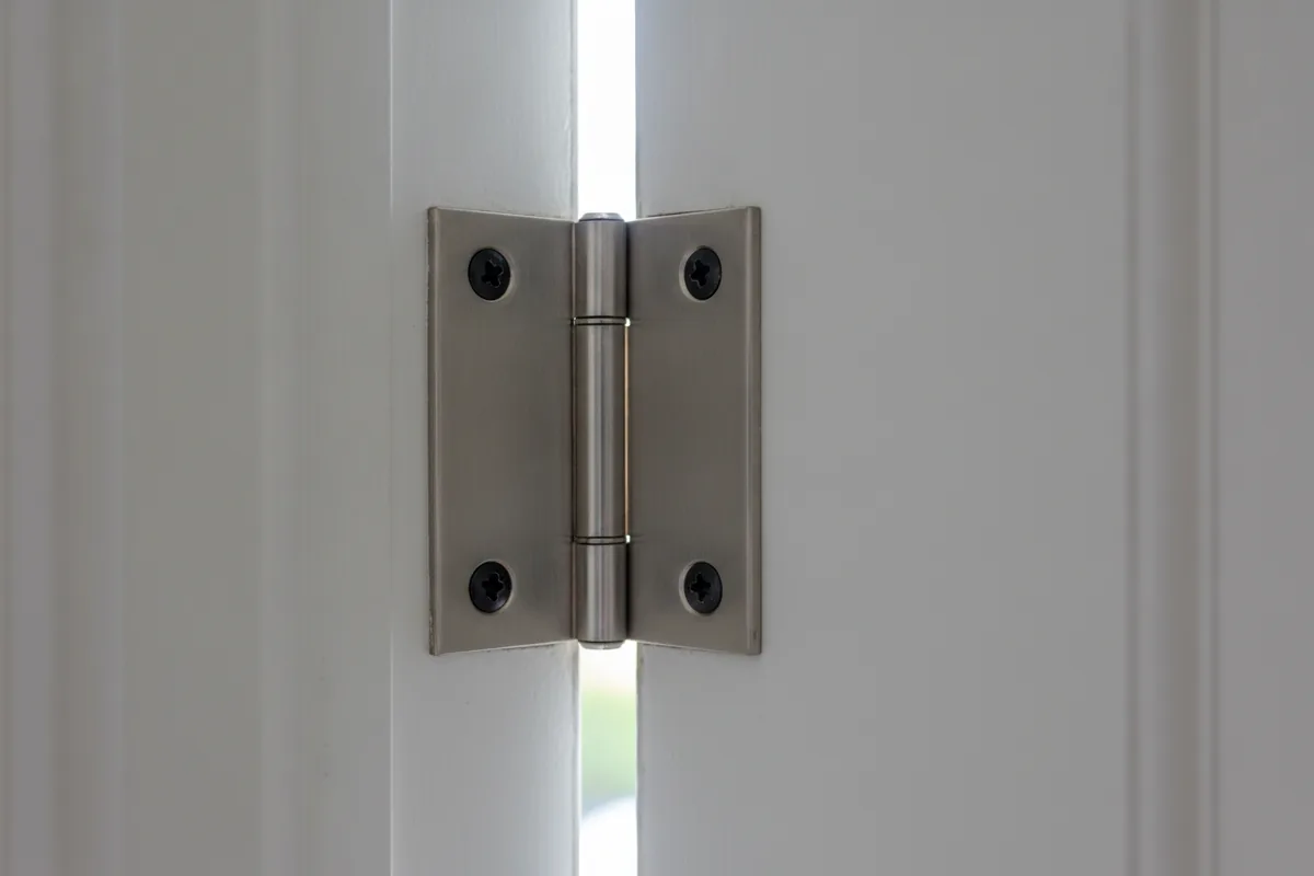 Close up of a door hinge mounted on the hinge jamb of an exterior door frame