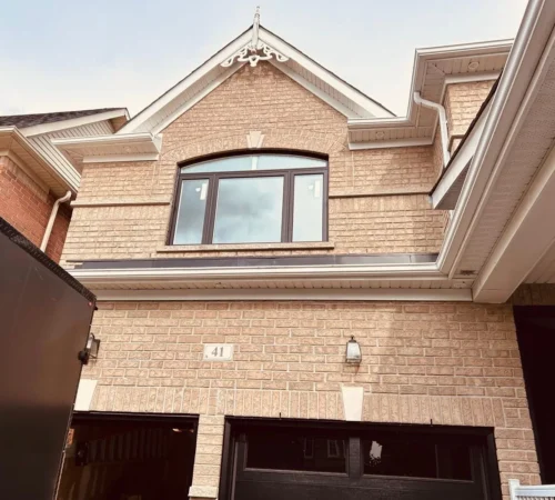Brown arched replacement window installed above a garage