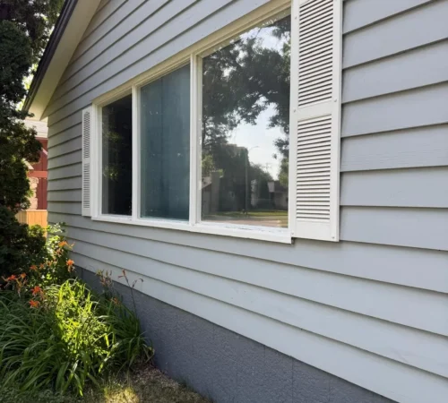Side view of the new front window and its exterior trim on grey siding
