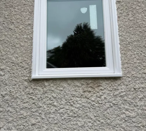 New white vinyl window set into the stucco wall from outside