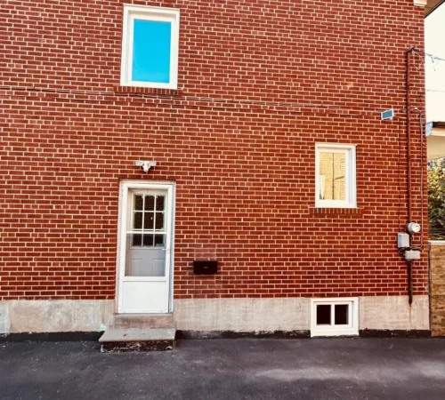 Side wall with new white windows and a basement sliding window